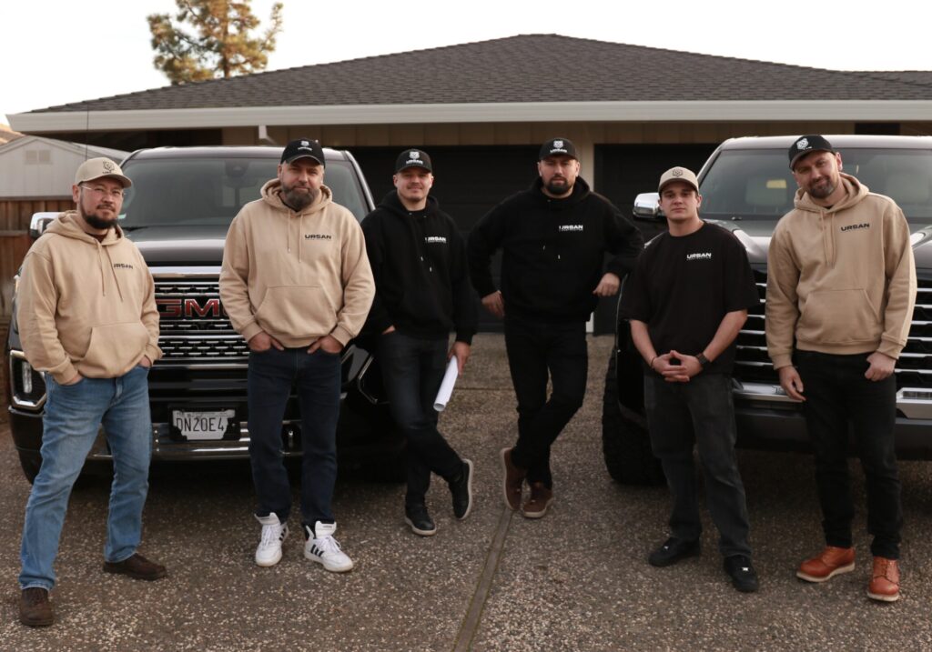 The full Ursan Construction remodeling team standing in front of work trucks.