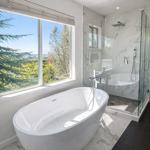 Modern white soaking tub placed under a large scenic window.