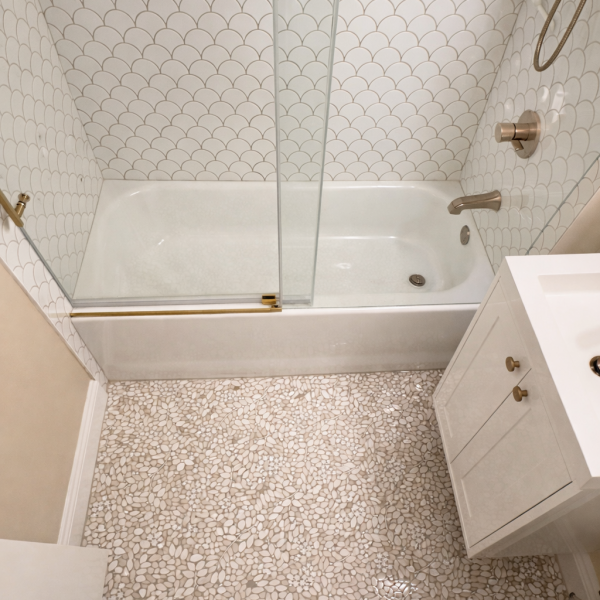 Completed bathroom remodel with glass shower door and white subway tiles.