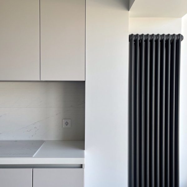 Modern kitchen storage solution with sleek vertical radiator and white walls.