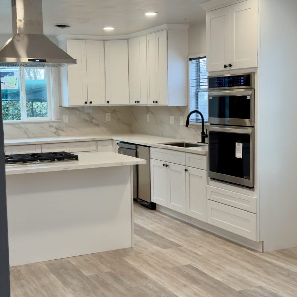 Bright modern kitchen renovation with white cabinets and professional oven.